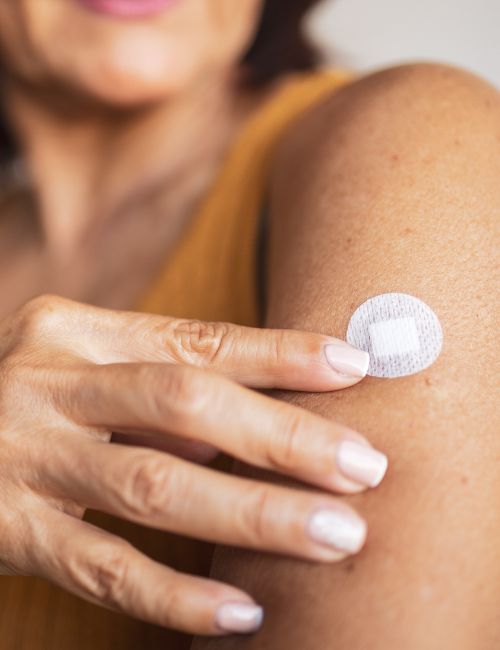 a woman pointing to a bandaid on her upper arm