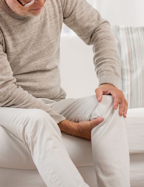 an older gentleman holding his knee from joint pain