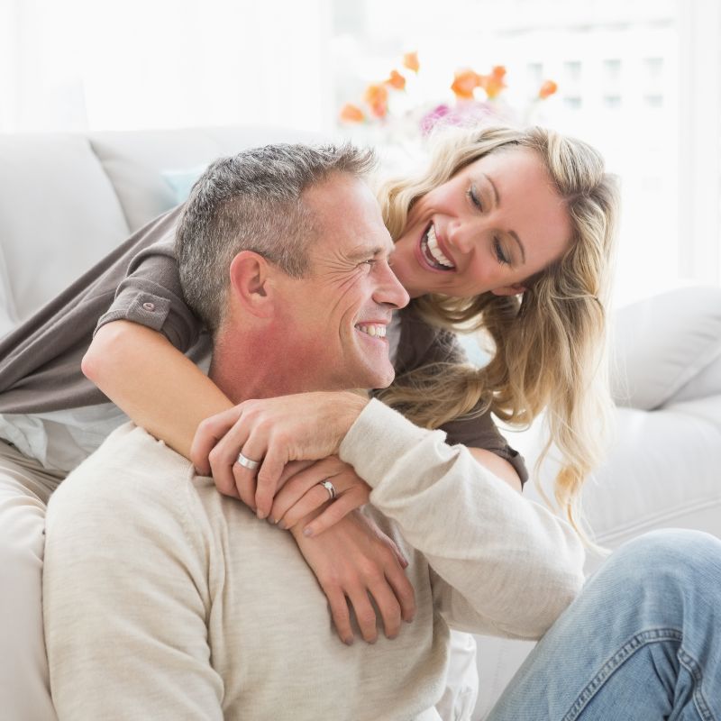 a woman and a man smiling while sitting on the floor