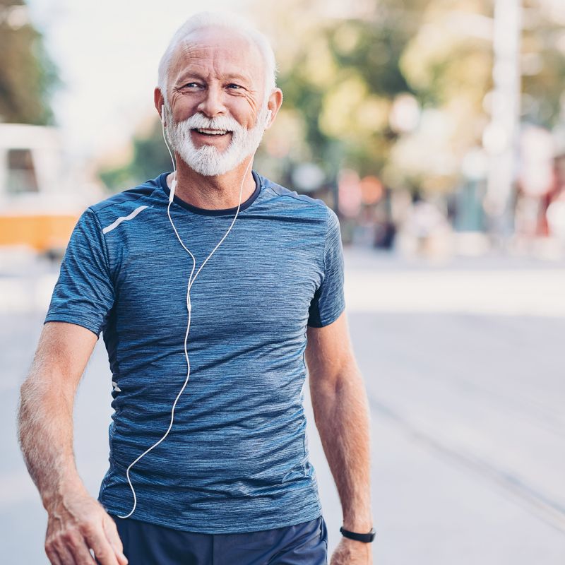 an older gentleman walking down a street with his headphones in his ears